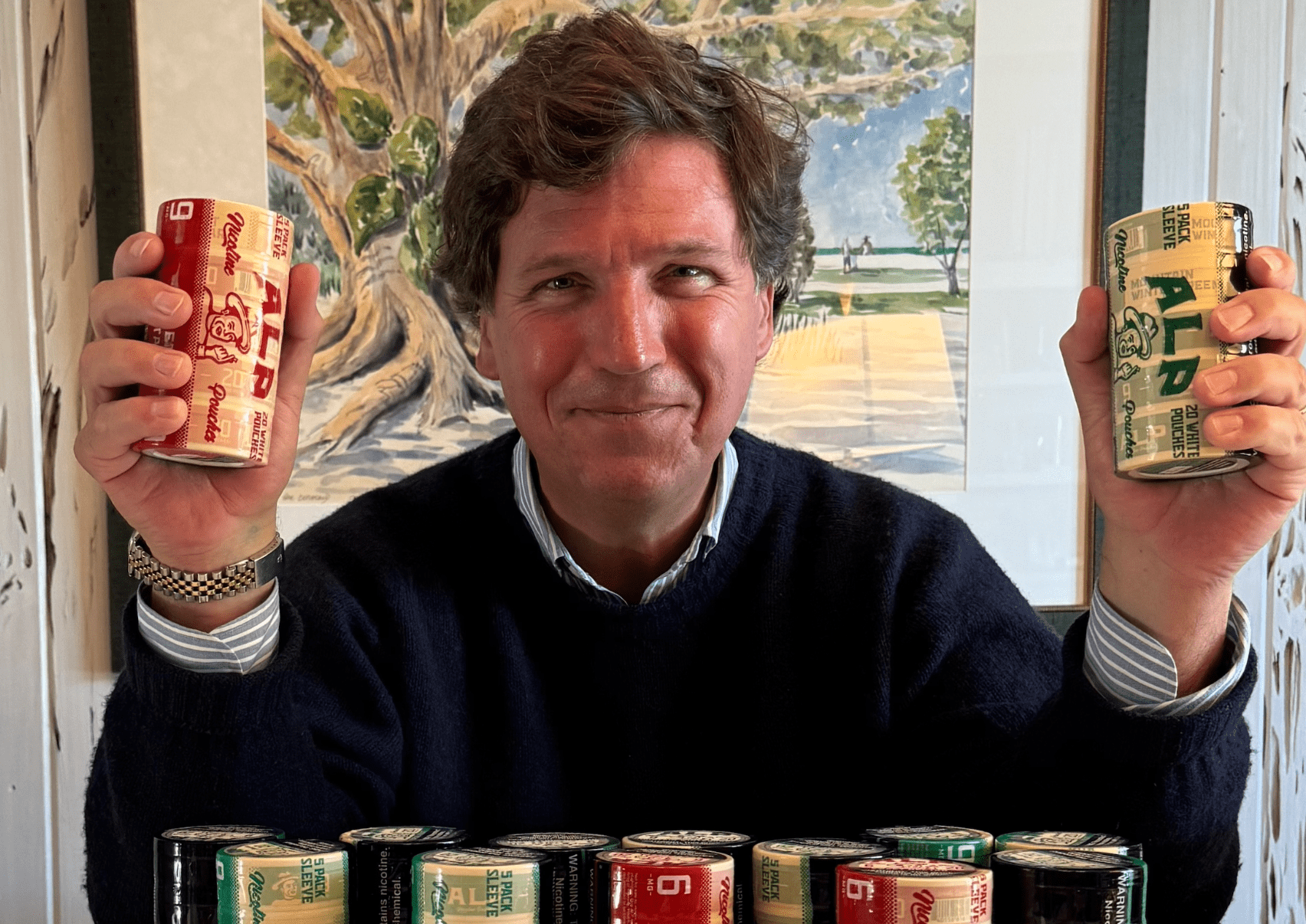 Tucker Carlson holding Alp tins